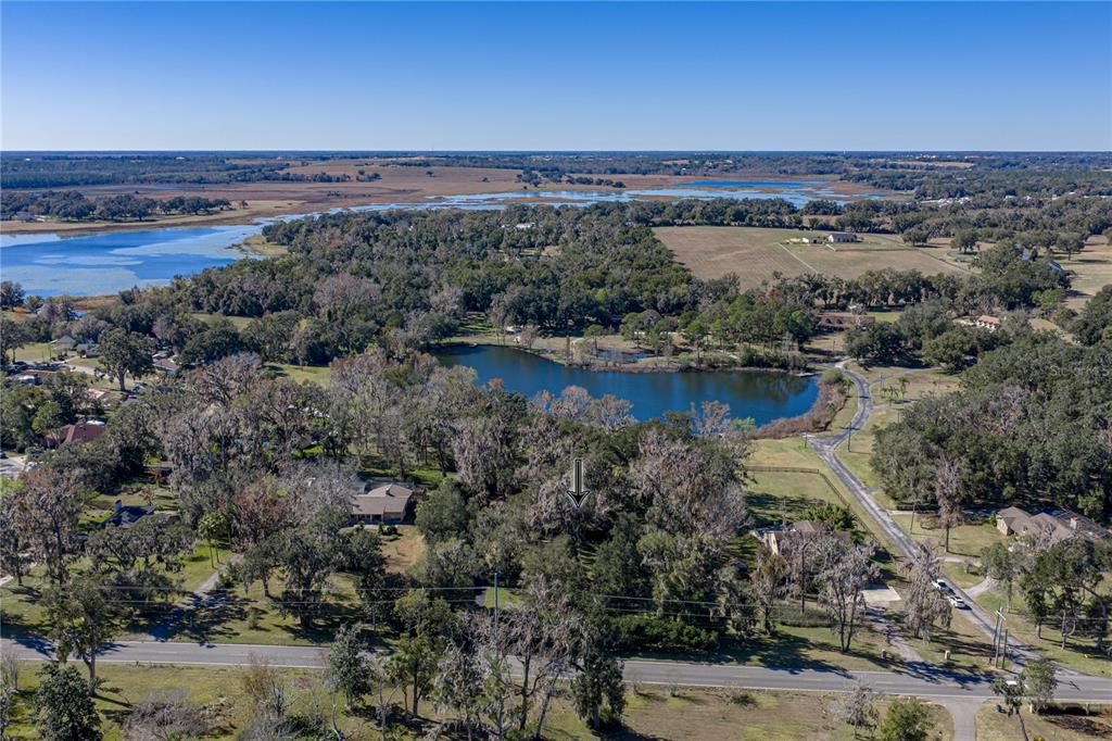 An aerial view shows a wooded lot with a downward-pointing arrow near a lake — 11045 FORT KING ROAD, DADE CITY, FL