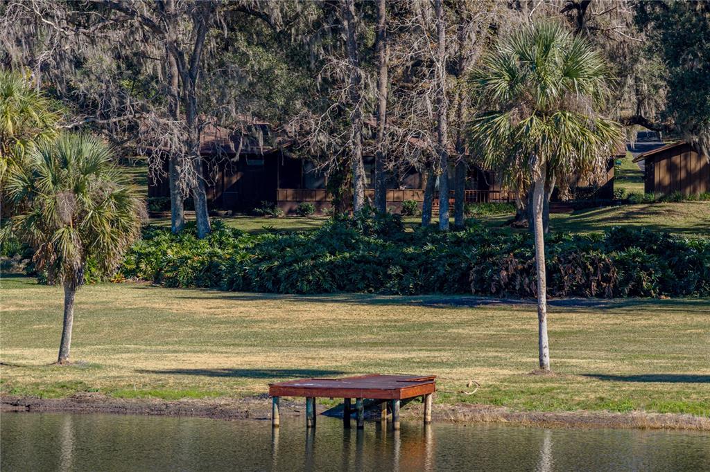 A wooden dock sits on a pond in front of a house surrounded by trees — 11045 FORT KING ROAD, DADE CITY, FL