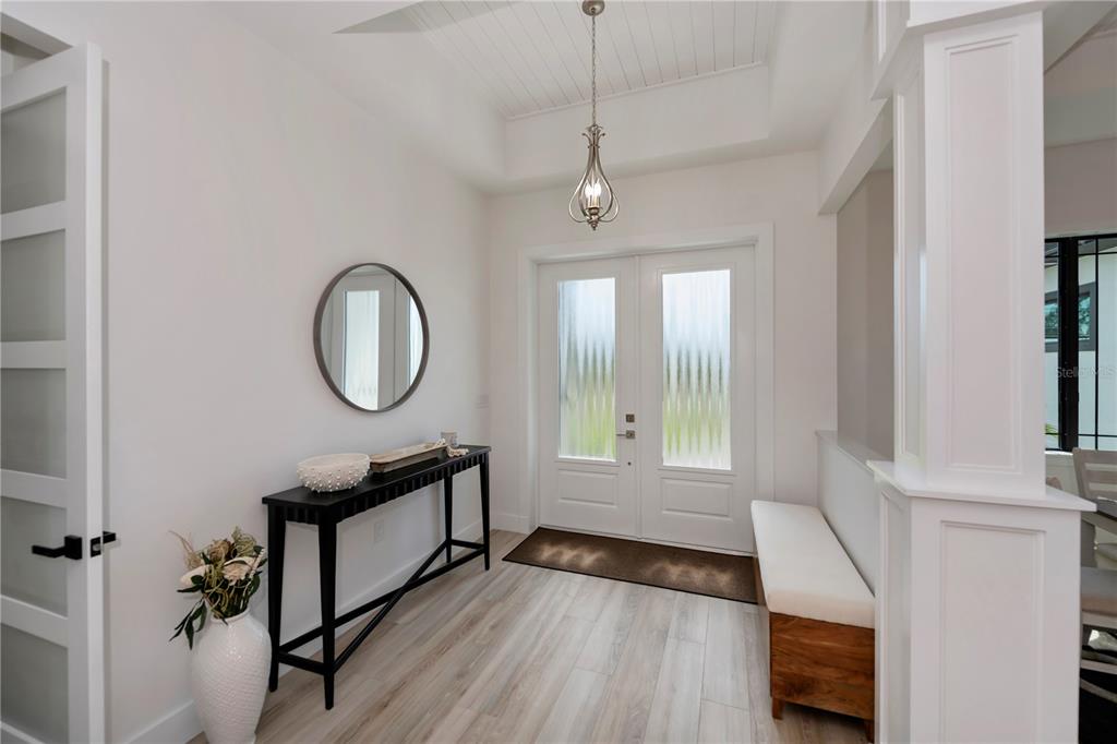 A bright entryway features white walls, light wood flooring, a console table, and double doors — 15384 VISALIA ROAD, PORT CHARLOTTE, FL