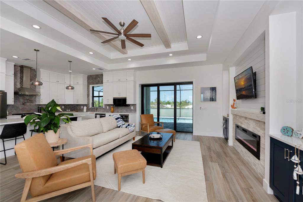 A living room with a fireplace, white sofa, two leather chairs, and an open kitchen — 15384 VISALIA ROAD, PORT CHARLOTTE, FL