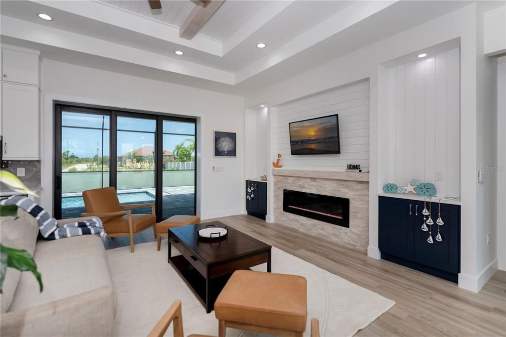 A living room features a fireplace, wall-mounted television, dark blue cabinets, and sliding glass doors — 15384 VISALIA ROAD, PORT CHARLOTTE, FL