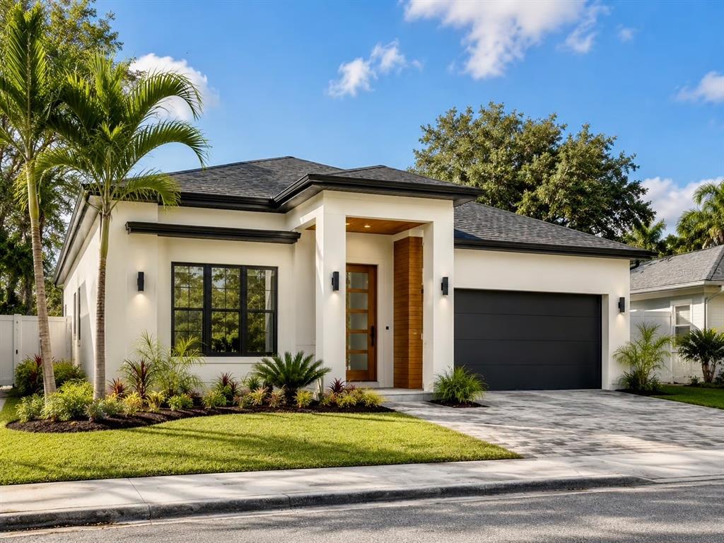 A modern single-story house with white stucco, a dark garage door, and a wood-accented entryway — 0 BLOSSOM AVENUE, TAMPA, FL