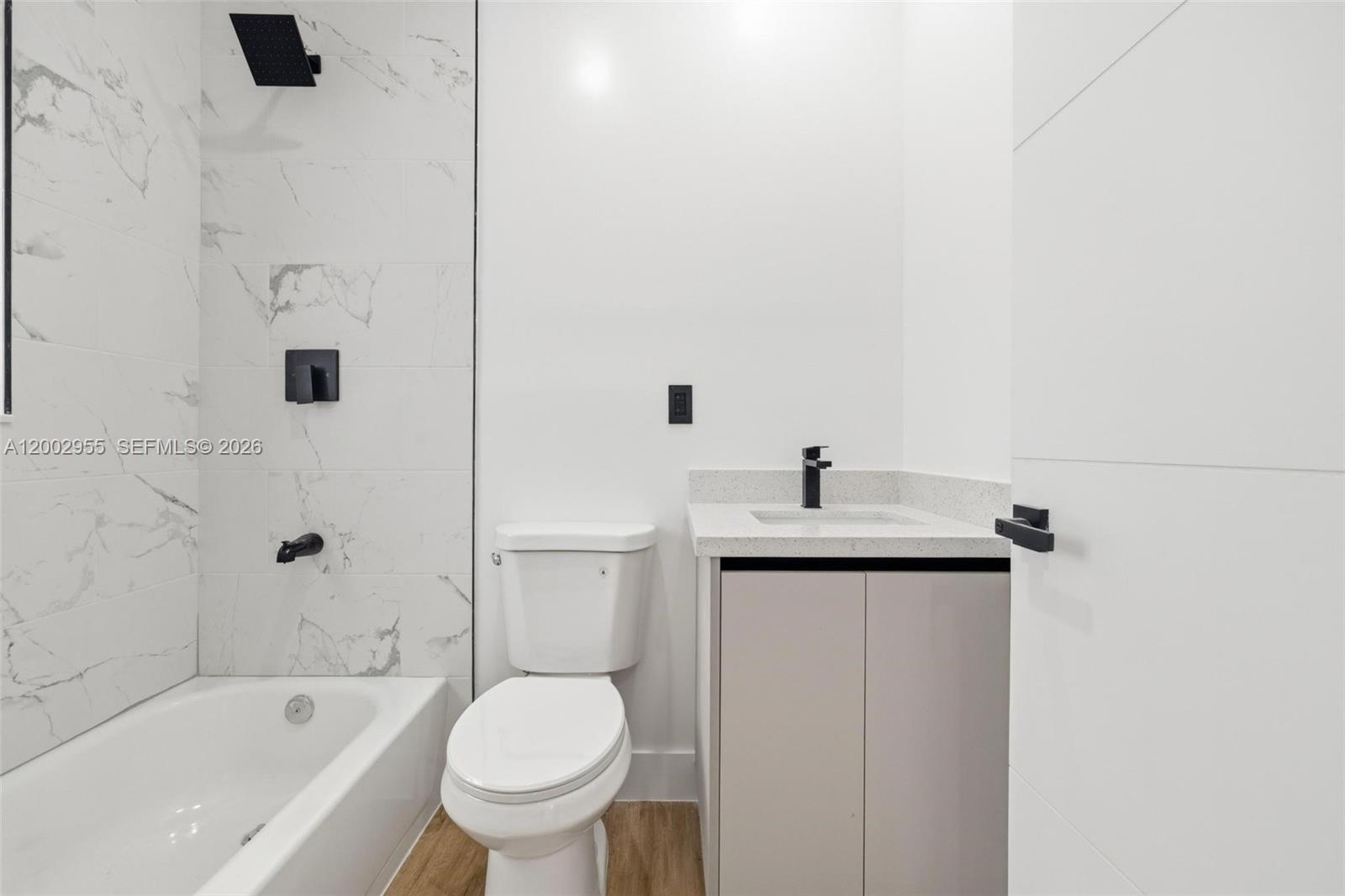 A modern bathroom features a white marble-tiled shower, a toilet, and a light-colored vanity — 4717 SW 32nd Ave, Dania Beach FL 33312, DANIA BEACH, FL