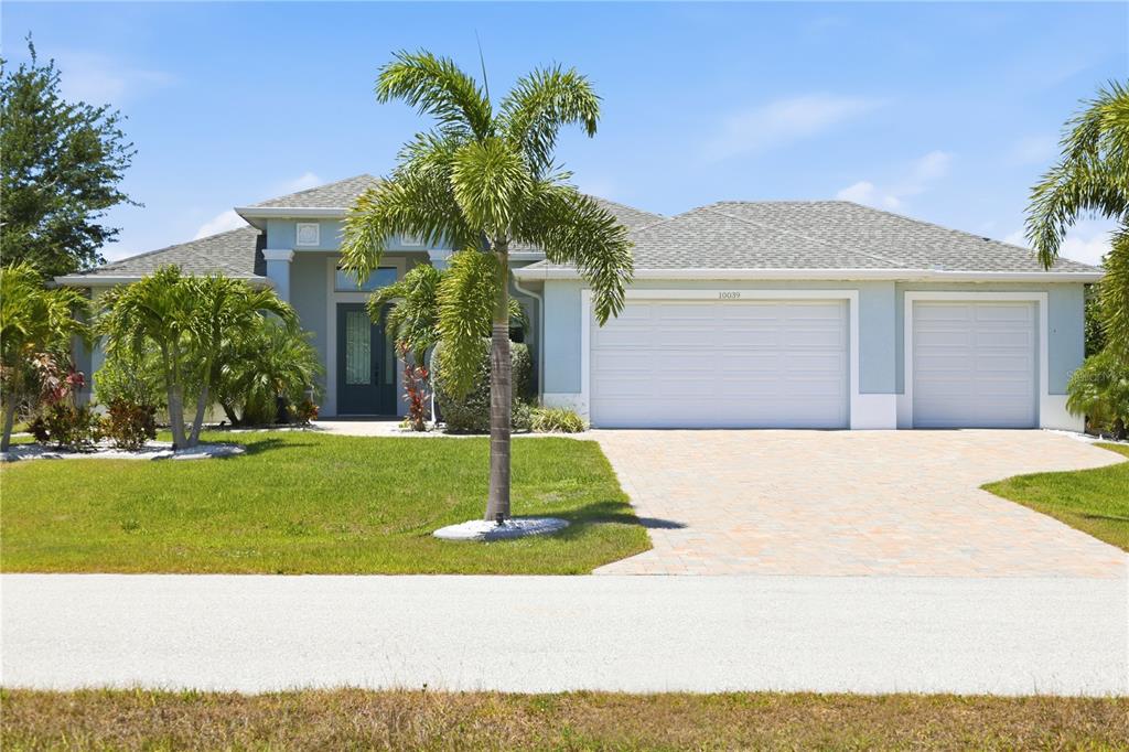 A single-story house with a three-car garage, palm trees, and a paved driveway — 10039 KINGSVILLE DRIVE, PORT CHARLOTTE, FL