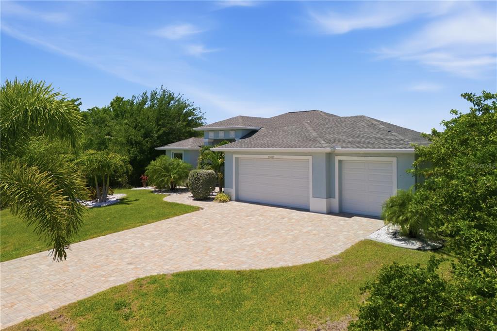 A light blue house with a paver driveway and a three-car garage — 10039 KINGSVILLE DRIVE, PORT CHARLOTTE, FL