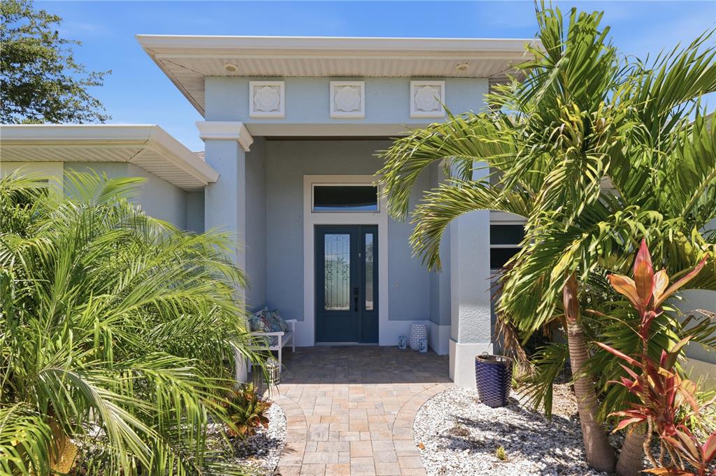 A light blue house exterior features a dark blue front door and a stone walkway — 10039 KINGSVILLE DRIVE, PORT CHARLOTTE, FL
