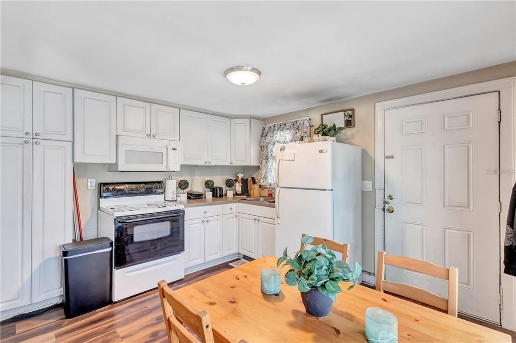 A kitchen with white cabinets, white appliances, and a wooden dining table in the foreground — 2521 4TH STREET S, ST PETERSBURG, FL