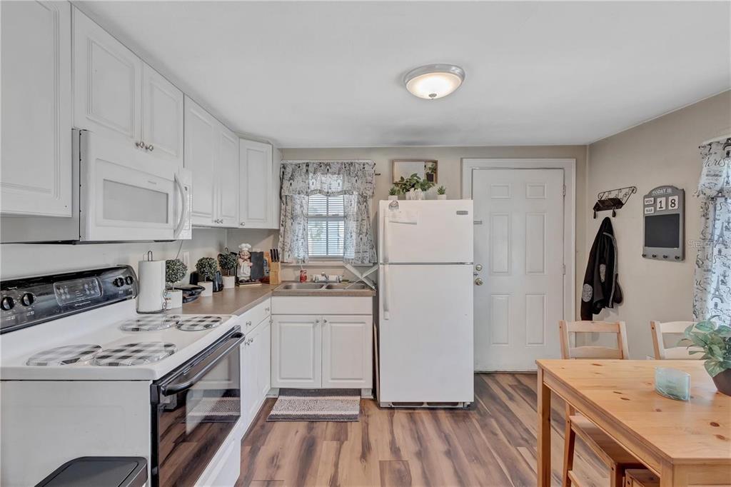A kitchen features white cabinetry, a white stove, a white refrigerator, and wood-look flooring — 2521 4TH STREET S, ST PETERSBURG, FL