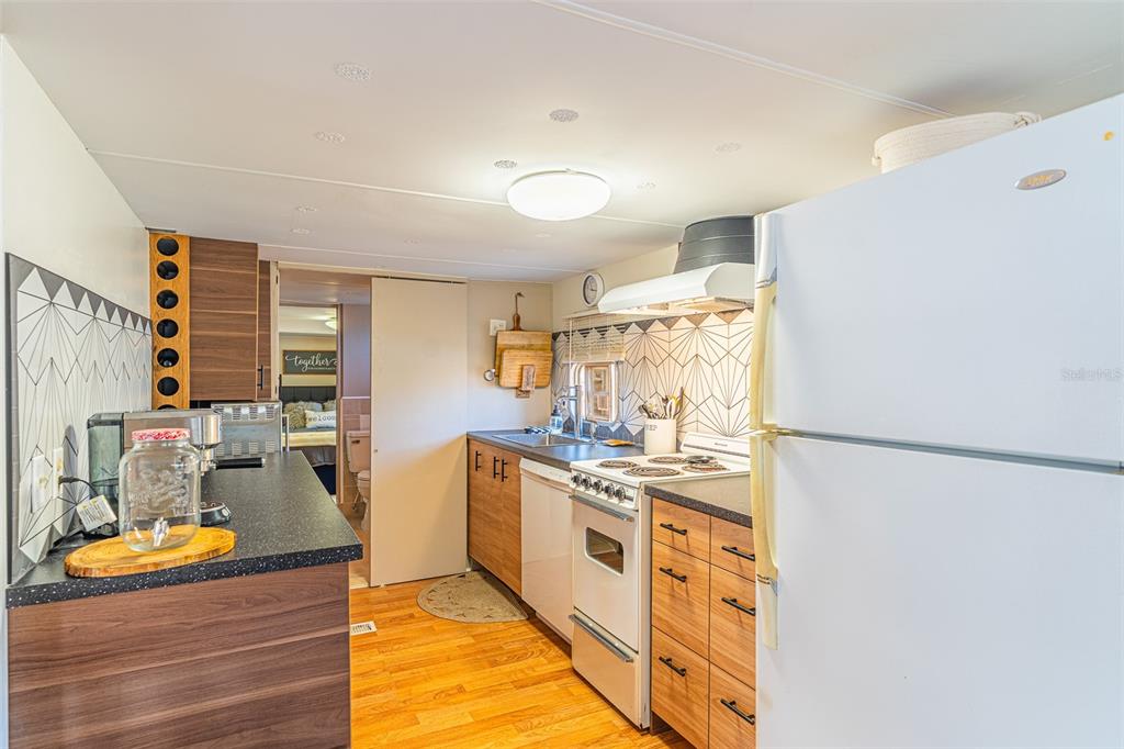 A kitchen features wood-grain cabinets, a white stove, a refrigerator, and a geometric tile backsplash — 77 SILVERSIDES STREET, LAKE WALES, FL