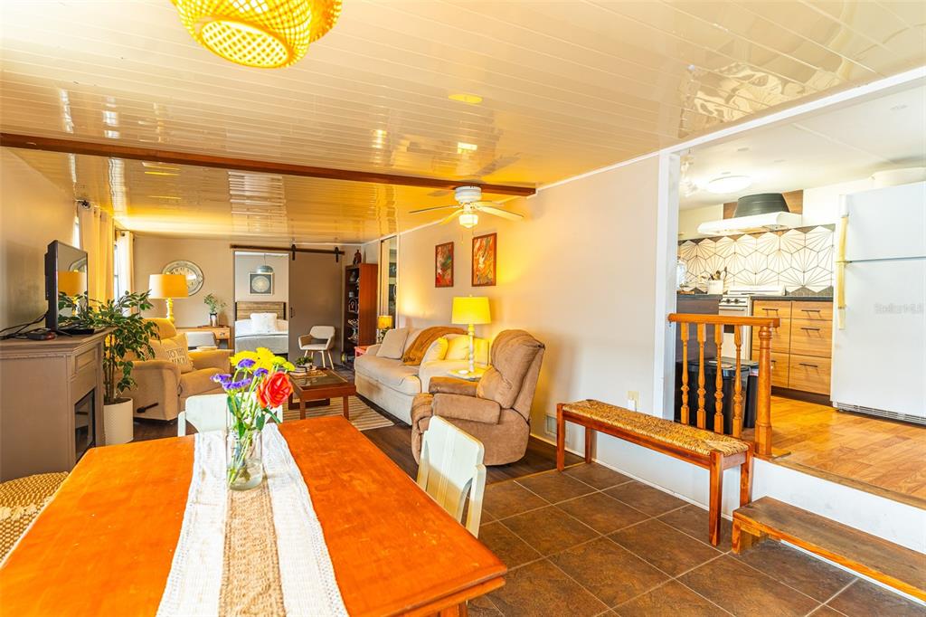 A dining area with a wooden table leads into a living room and an elevated kitchen — 77 SILVERSIDES STREET, LAKE WALES, FL