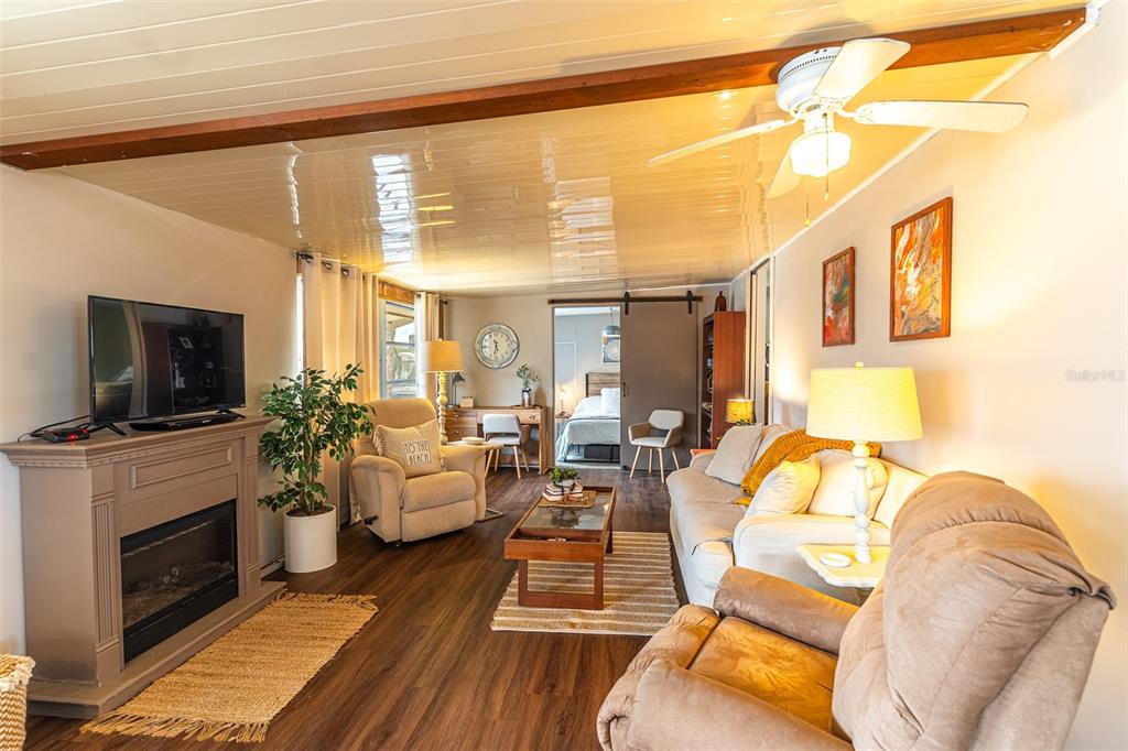 A living room features a fireplace, a ceiling fan, wood-look flooring, and a sliding door — 77 SILVERSIDES STREET, LAKE WALES, FL