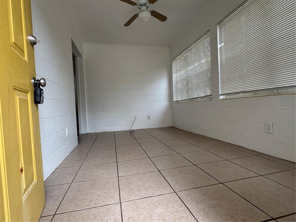 A sunroom with white block walls, tiled floors, a ceiling fan, and two windows — 4418 ELI STREET, ORLANDO, FL