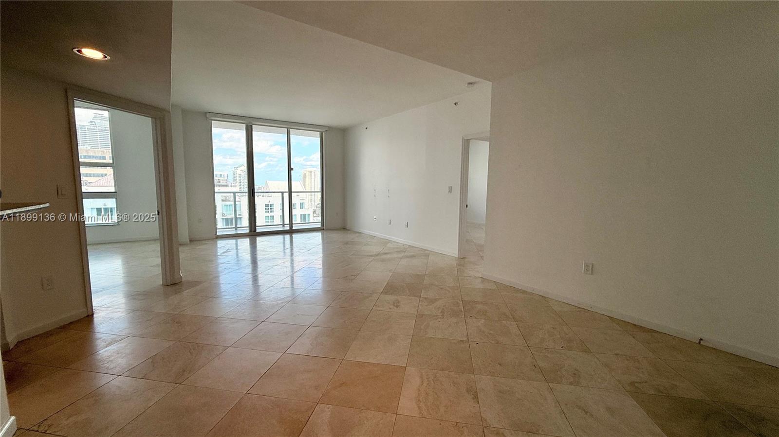 An empty living area features light-colored tile flooring, white walls, and floor-to-ceiling glass doors — 1155 Brickell Bay Dr, Miami FL 33131, MIAMI, FL