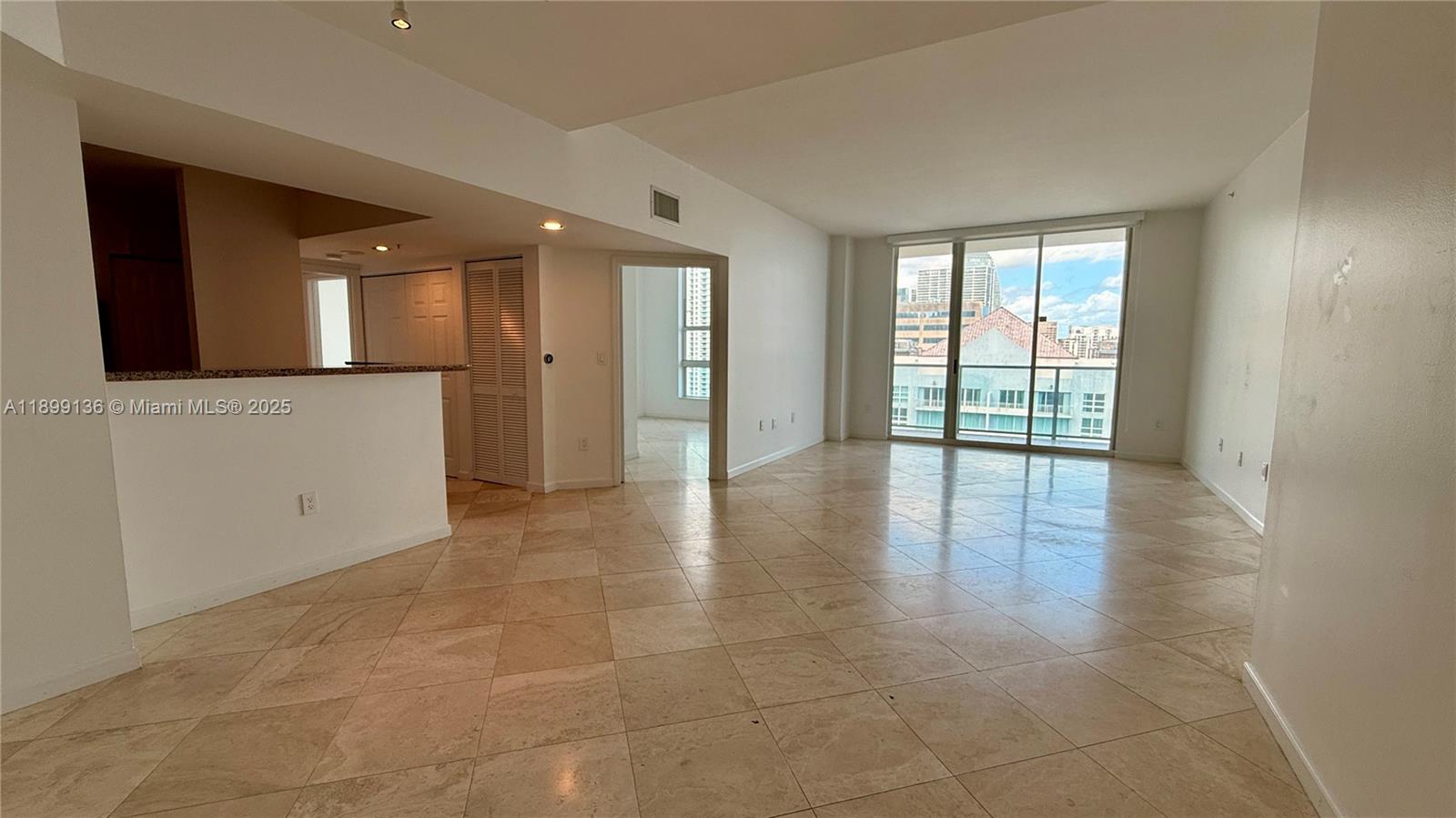 An open-concept living area features light-colored tile flooring, white walls, and a large balcony window — 1155 Brickell Bay Dr, Miami FL 33131, MIAMI, FL
