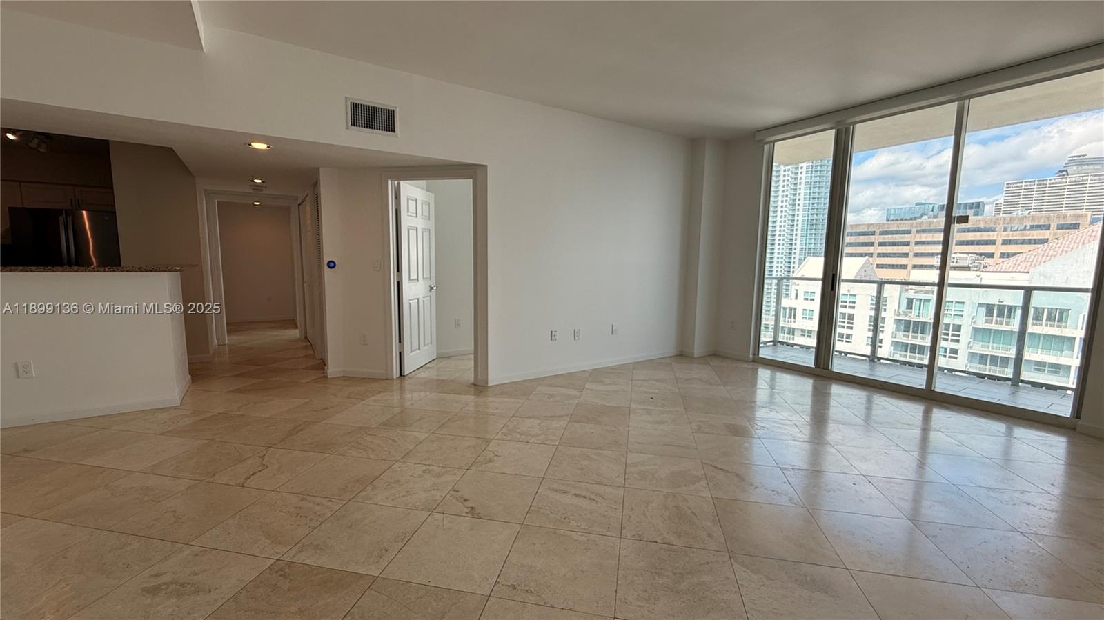 An empty living area features light-colored tile flooring, white walls, and a balcony with city views — 1155 Brickell Bay Dr, Miami FL 33131, MIAMI, FL