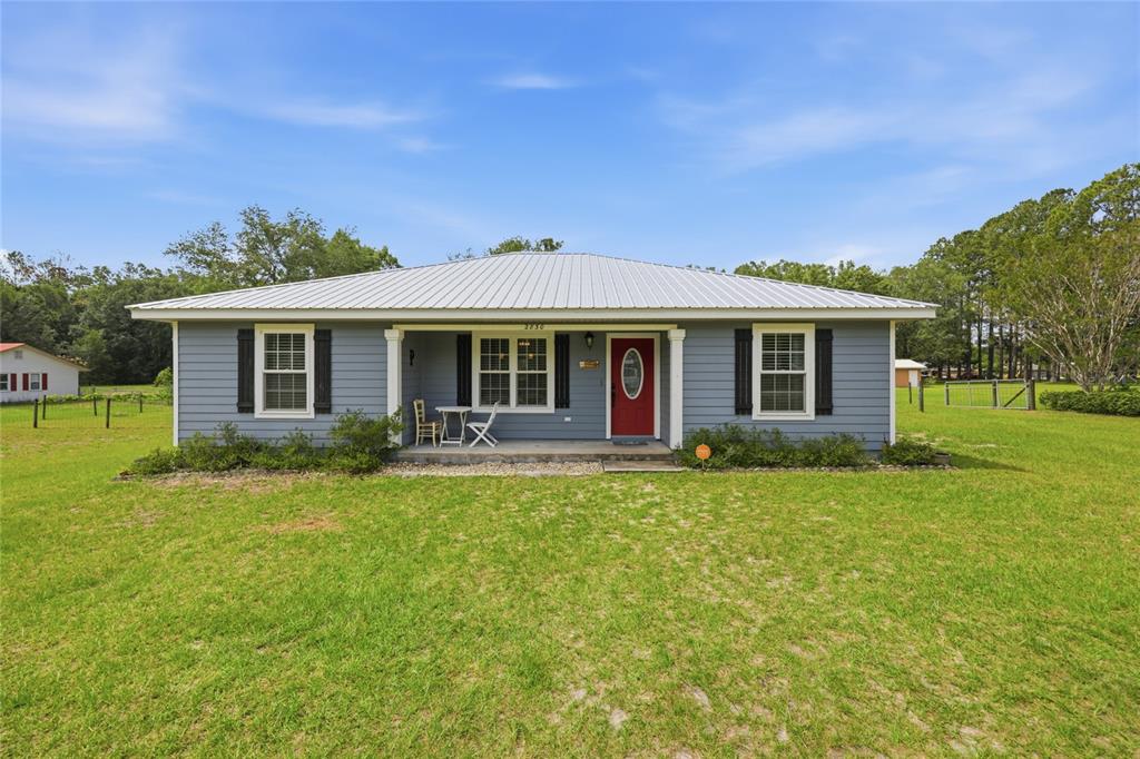 A single-story house with blue siding, a metal roof, and a red front door — 2830 NW 174 STREET, TRENTON, FL