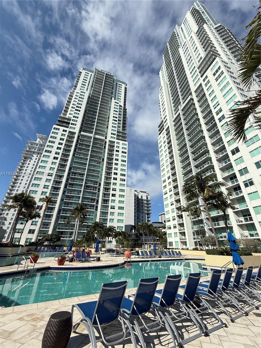 A swimming pool area with lounge chairs sits in front of two tall residential towers — 253 NE 2nd St # 908, Miami FL 33132, MIAMI, FL