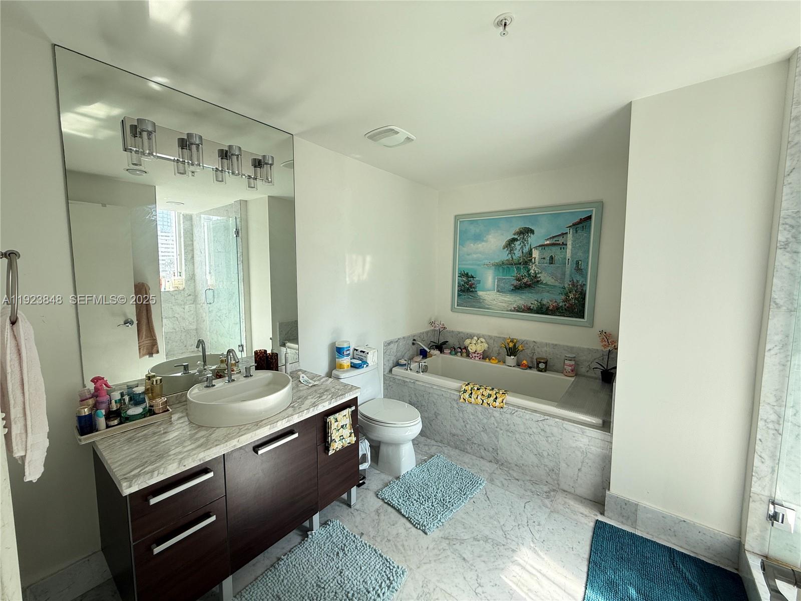 A bathroom features a dark wood vanity, marble countertops, a soaking tub, and tiled floors — 253 NE 2nd St # 908, Miami FL 33132, MIAMI, FL