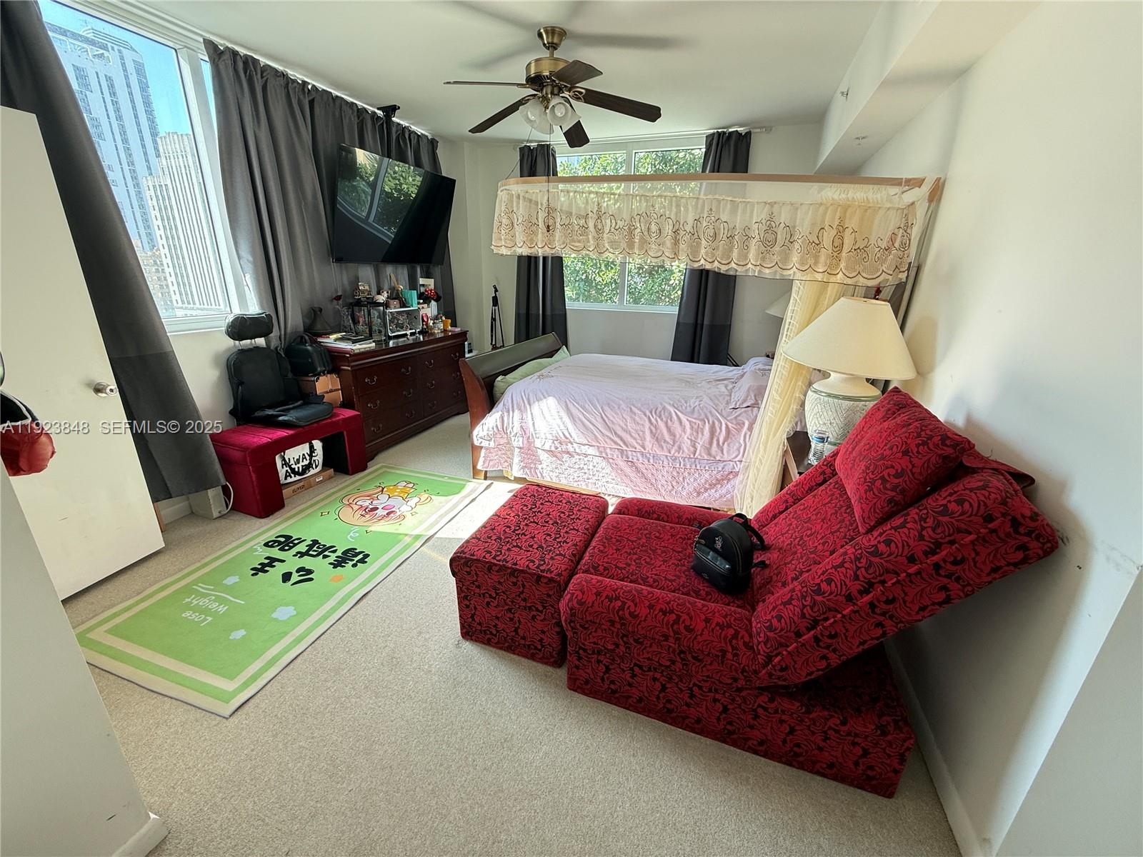 A bedroom features a canopy bed, a red recliner, a dresser, and a city view — 253 NE 2nd St # 908, Miami FL 33132, MIAMI, FL