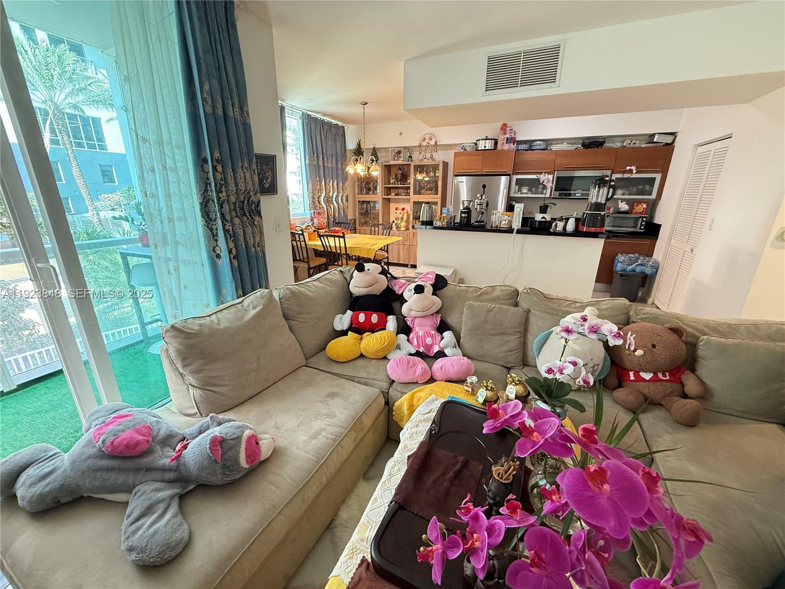 A living room features a sectional sofa with plush toys, an adjacent kitchen, and balcony access — 253 NE 2nd St # 908, Miami FL 33132, MIAMI, FL