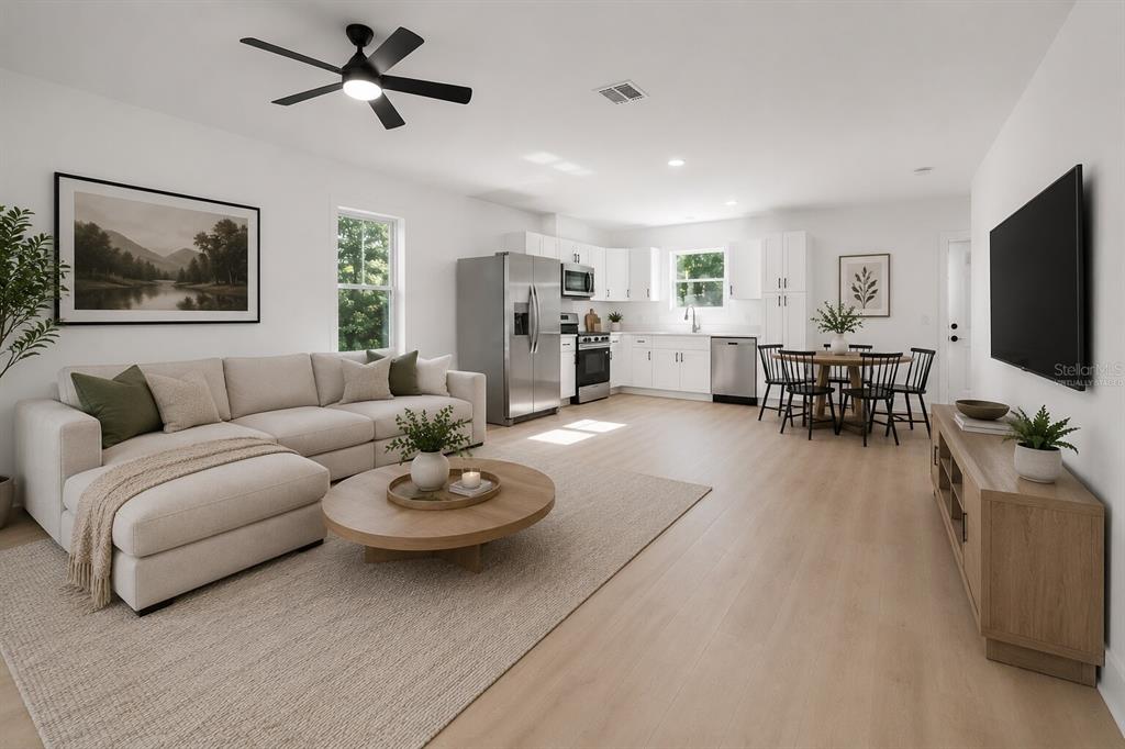 An open-concept living room and kitchen featuring light wood floors, white cabinetry, and neutral furniture — 2013 AVA CIRCLE, BARTOW, FL