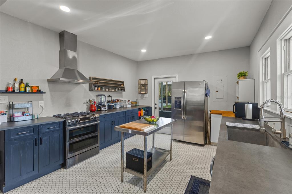 A kitchen features blue cabinets, stainless steel appliances, a center island, and hexagonal floor tiles — 1413 N OSCEOLA AVENUE, CLEARWATER, FL