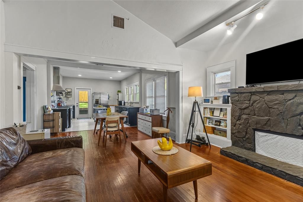 A living room with a stone fireplace and hardwood floors opens into a kitchen area — 1413 N OSCEOLA AVENUE, CLEARWATER, FL