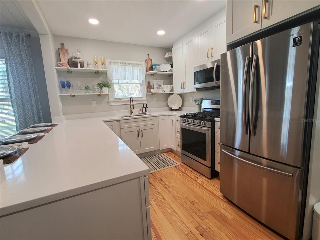 A kitchen features white cabinetry, stainless steel appliances, open shelving, and a large island — 410 N OLEANDER AVENUE, DAYTONA BEACH, FL