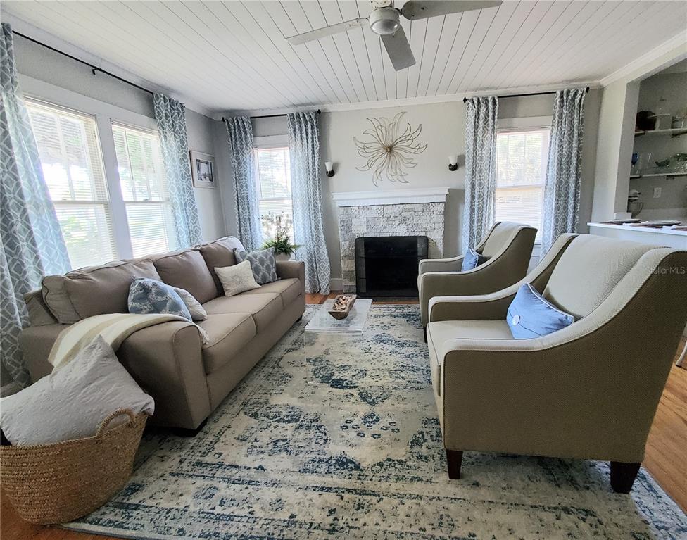 A living room features a stone fireplace, a beige sofa, two armchairs, and a patterned rug — 410 N OLEANDER AVENUE, DAYTONA BEACH, FL
