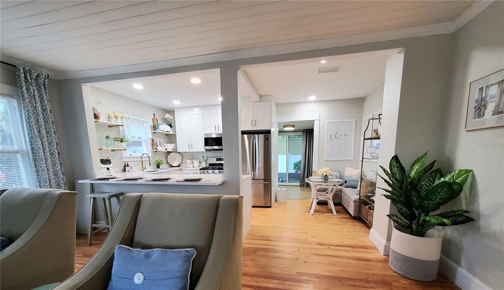 An open-concept living area features a kitchen with white cabinets, a breakfast bar, and hardwood floors — 410 N OLEANDER AVENUE, DAYTONA BEACH, FL
