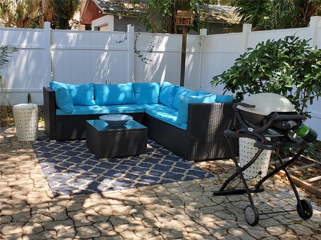 A patio features a wicker sectional sofa with blue cushions, a coffee table, and a grill — 410 N OLEANDER AVENUE, DAYTONA BEACH, FL