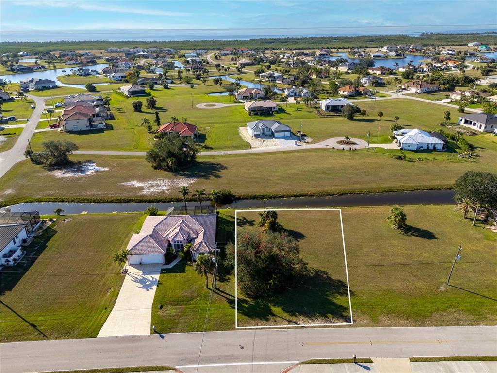 An aerial view shows a vacant residential lot next to a house near a canal — 17277 CAPE HORN BOULEVARD, PUNTA GORDA, FL