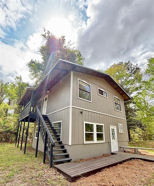 A two-story house with gray vertical siding, a wooden deck, and an exterior staircase — 18917 NW COUNTY ROAD 239, ALACHUA, FL