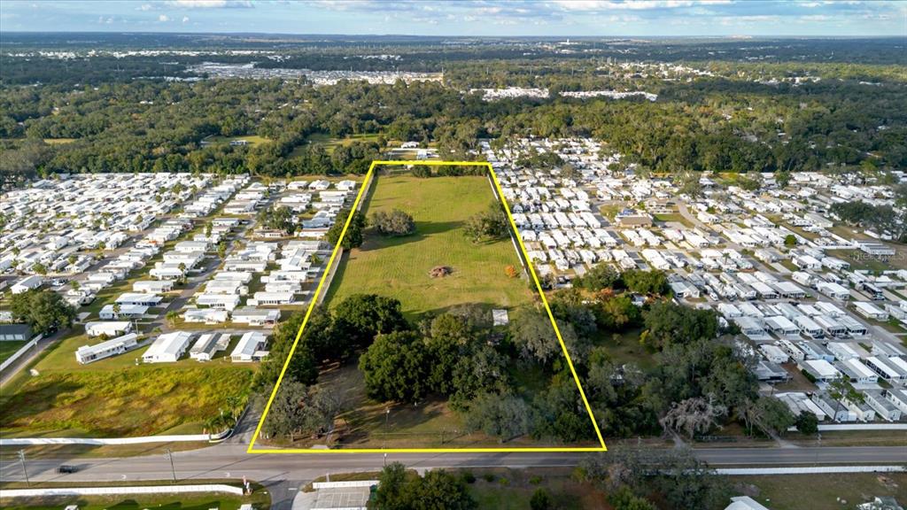 An aerial view shows a rectangular, tree-lined vacant lot situated between two mobile home parks — 37435 CHANCEY ROAD, ZEPHYRHILLS, FL