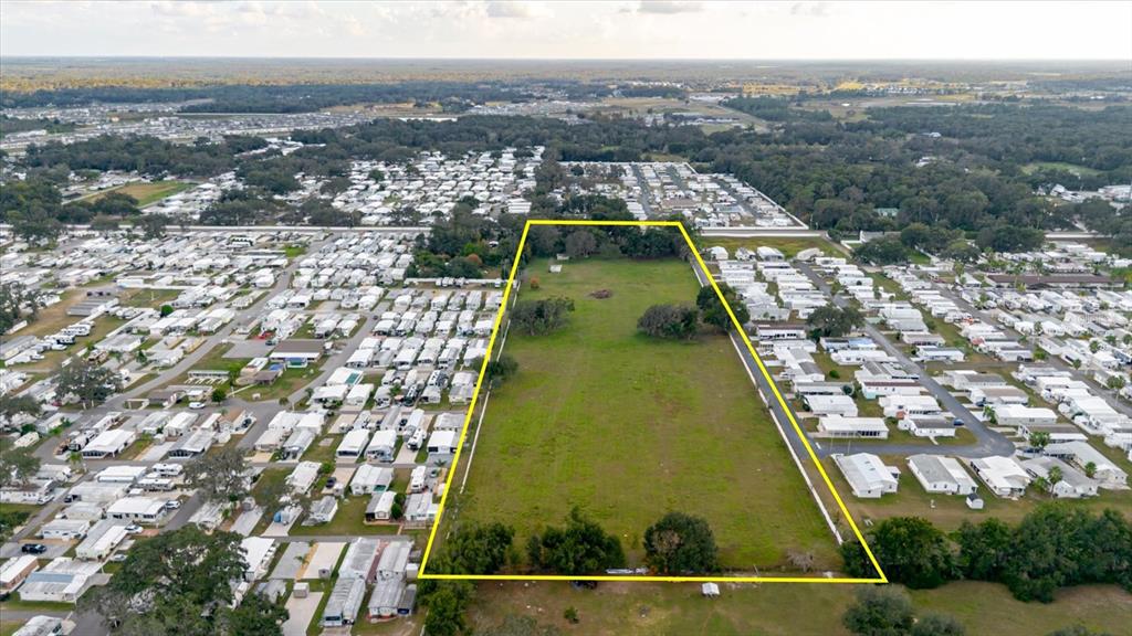 An aerial view shows a rectangular, grassy vacant lot surrounded by a mobile home park — 37435 CHANCEY ROAD, ZEPHYRHILLS, FL