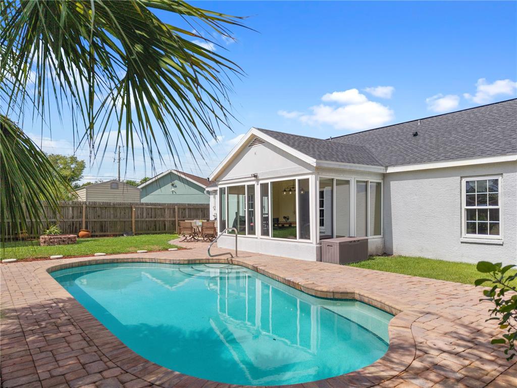 A backyard features a swimming pool with brick pavers and a sunroom attached to a house — 3320 5TH DRIVE W, PALMETTO, FL