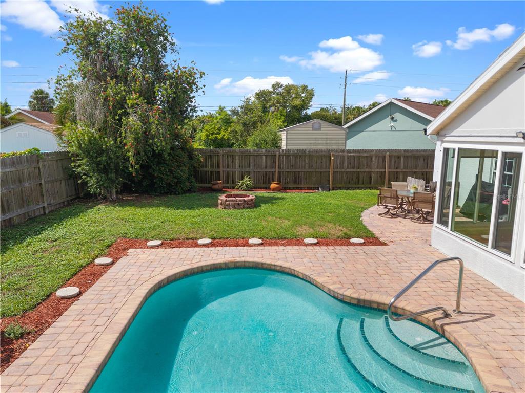 A backyard features a swimming pool, a brick patio, a fire pit, and a wooden fence — 3320 5TH DRIVE W, PALMETTO, FL