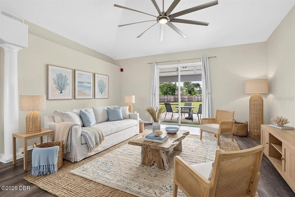 A living room features a white sofa, natural wood coffee table, and sliding glass patio doors — 1901 EDEN DRIVE, DELTONA, FL
