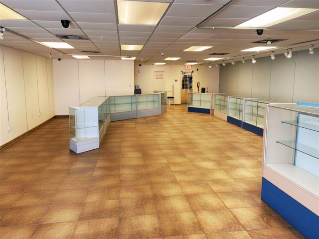 An empty retail space features glass display cases, a drop ceiling, and tiled flooring — 2016 S ATLANTIC AVENUE, DAYTONA BEACH, FL