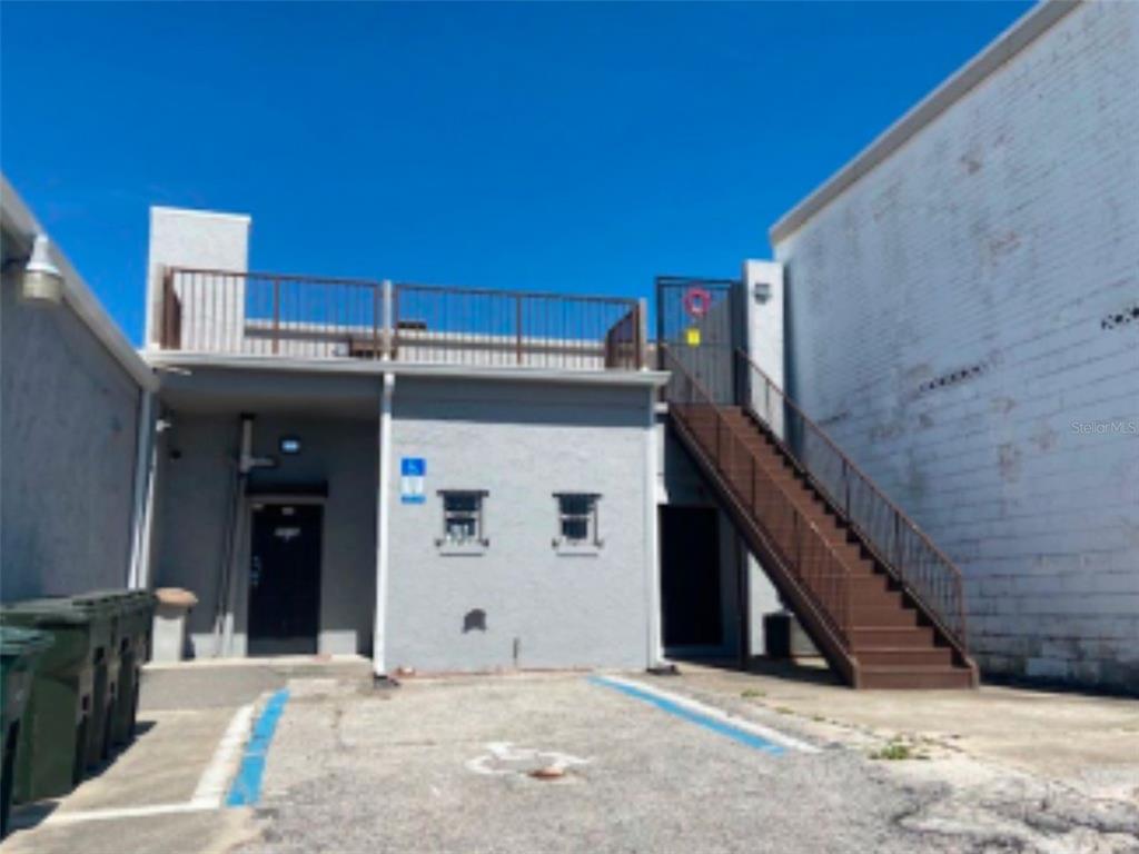 The exterior view shows a gray building with a metal staircase leading to a rooftop deck — 2016 S ATLANTIC AVENUE, DAYTONA BEACH, FL