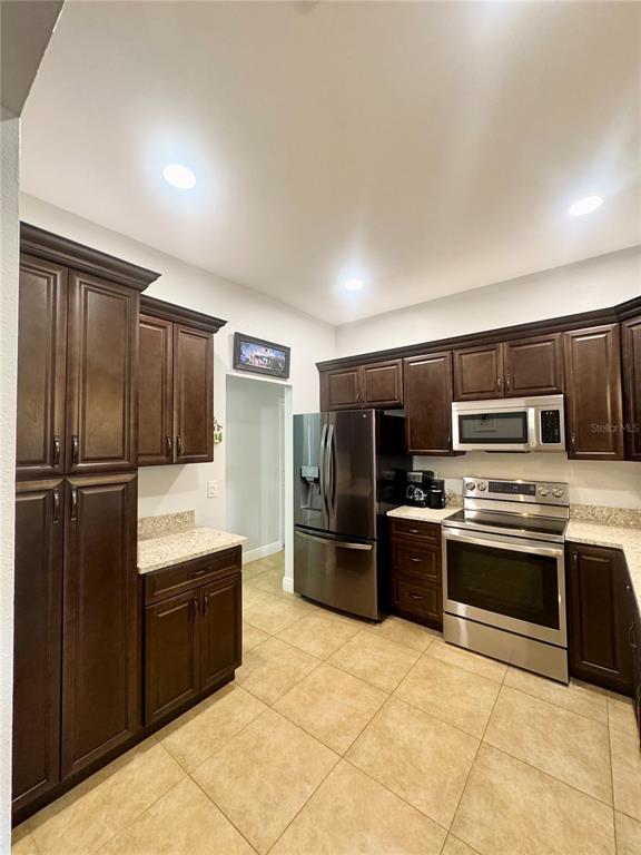A kitchen features dark wood cabinets, stainless steel appliances, and light-colored granite countertops — 106 CARLI COURT UNIT 106, LAKE MARY, FL