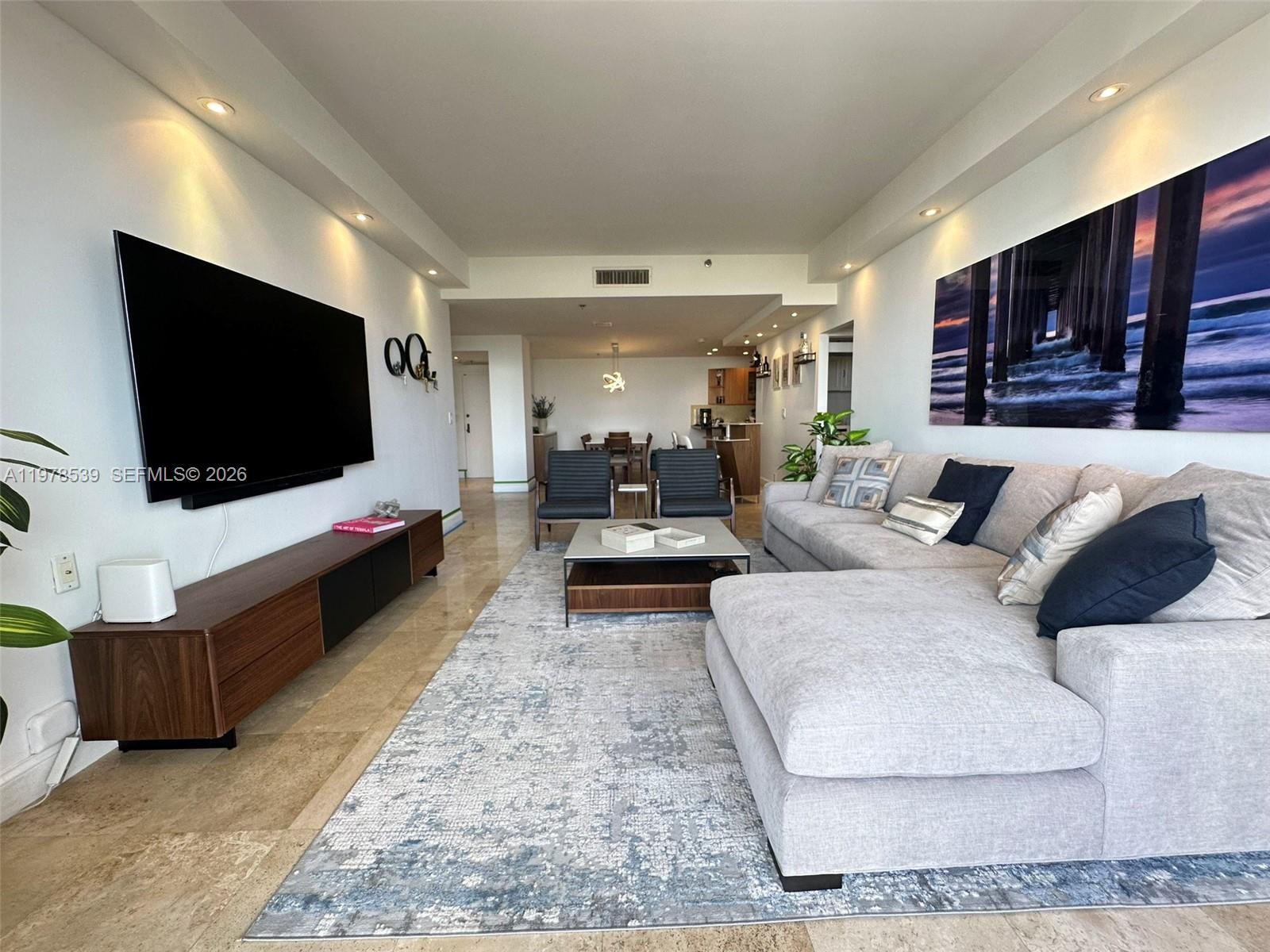 A modern living room features a large sectional sofa, wall-mounted television, and area rug — 251 Crandon Blvd # 606, Key Biscayne FL 33149, KEY BISCAYNE, FL