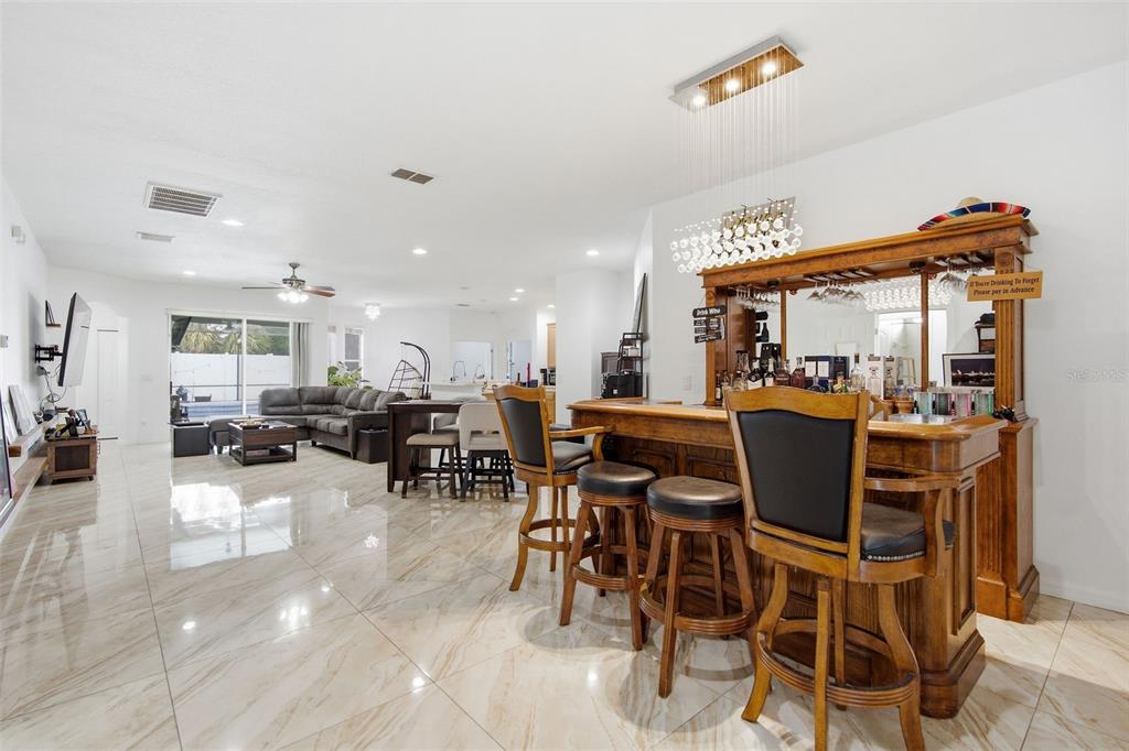 A spacious living area features a home bar with stools and polished tile flooring — 508 DEBRA DRIVE, BRANDON, FL
