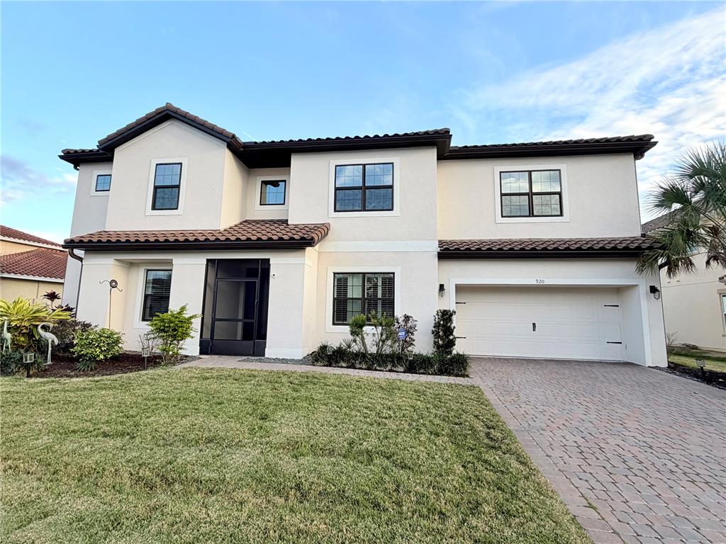 A two-story stucco house with a tile roof, a screened entryway, and a two-car garage — 920 WINDLASS COURT, KISSIMMEE, FL