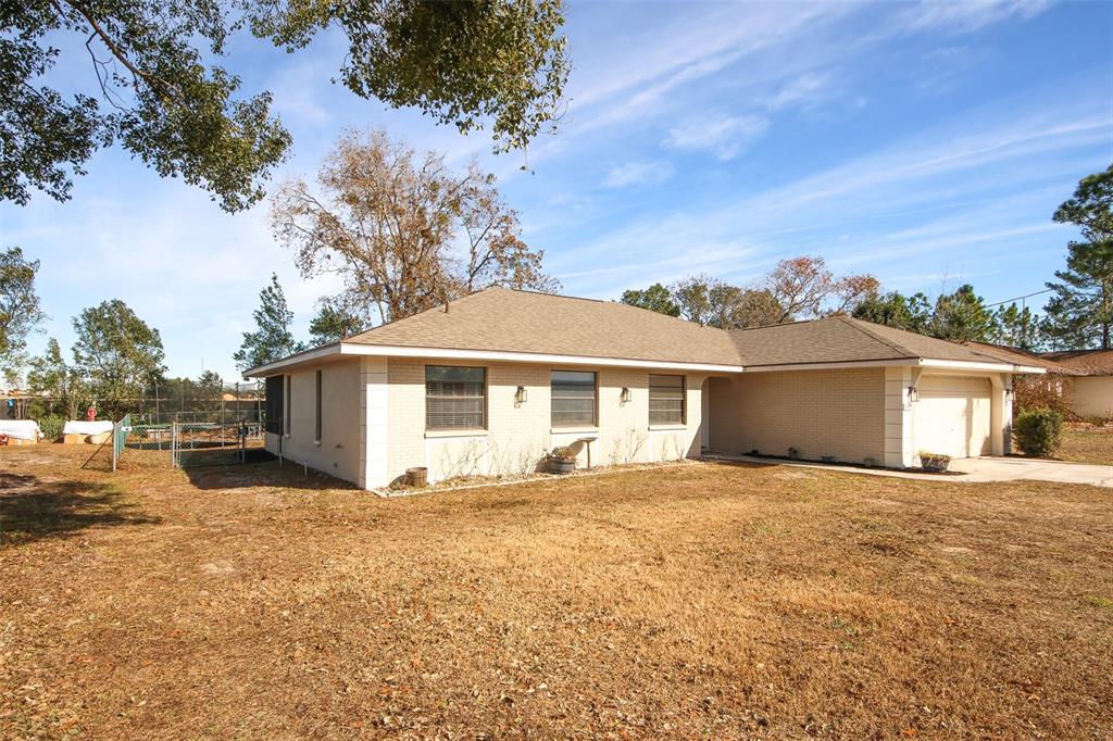 A single-story, light-colored brick house with a shingled roof and an attached garage — 13277 DELBARTON STREET, SPRING HILL, FL