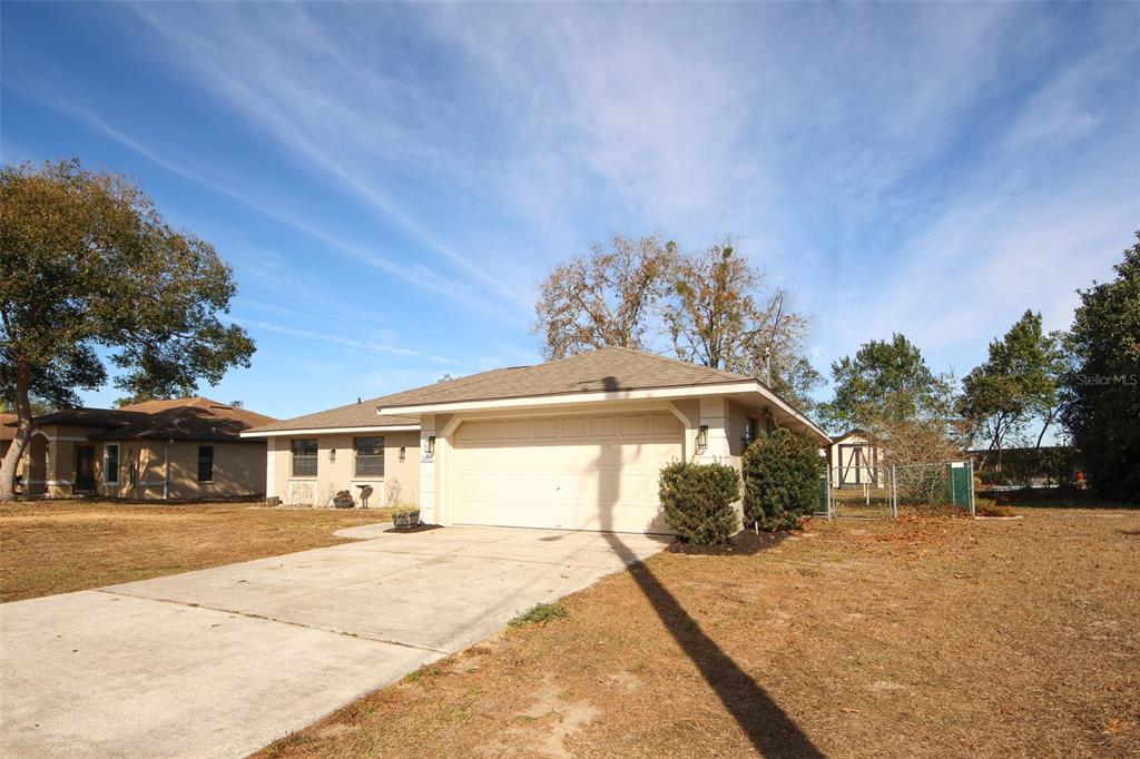 A single-story house with a beige exterior, a two-car garage, and a concrete driveway — 13277 DELBARTON STREET, SPRING HILL, FL