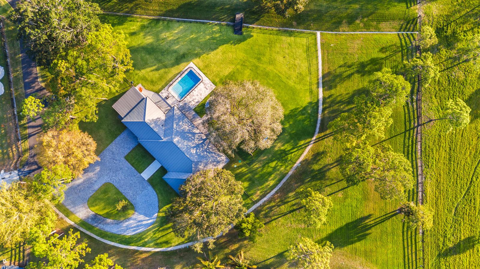An aerial view shows a house with a metal roof, swimming pool, and circular driveway — 20000 SE Mack Dairy Road SE, Jupiter FL 33478, JUPITER, FL