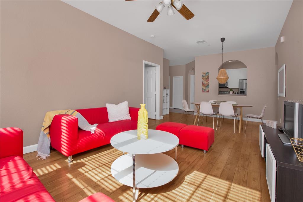 A living room features red sofas, a white tiered coffee table, and an adjacent dining area — 3190 DANTE DRIVE UNIT 304, ORLANDO, FL