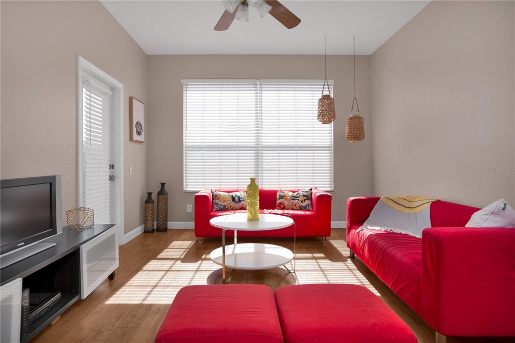 A living room features two red sofas, a white coffee table, and wood-look flooring — 3190 DANTE DRIVE UNIT 304, ORLANDO, FL