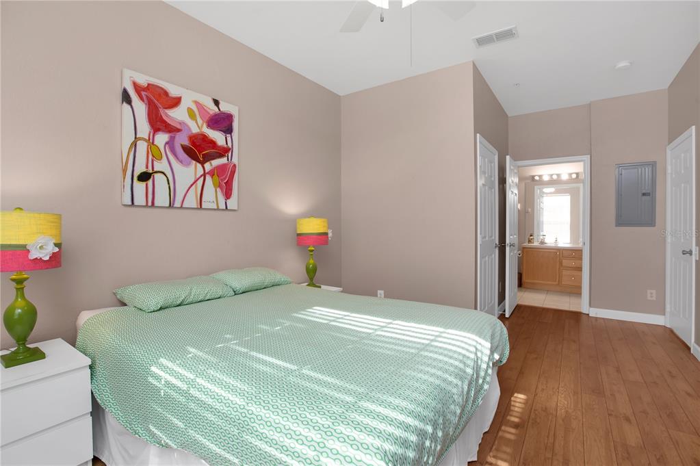 A bedroom features a bed with a green patterned quilt, two lamps, and an attached bathroom — 3190 DANTE DRIVE UNIT 304, ORLANDO, FL